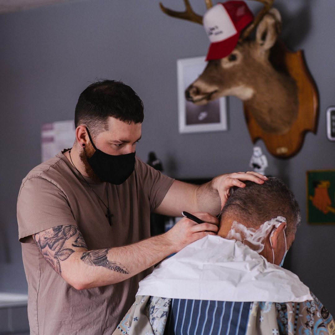 Kiefer fading out the hair of a customer with a straight razor