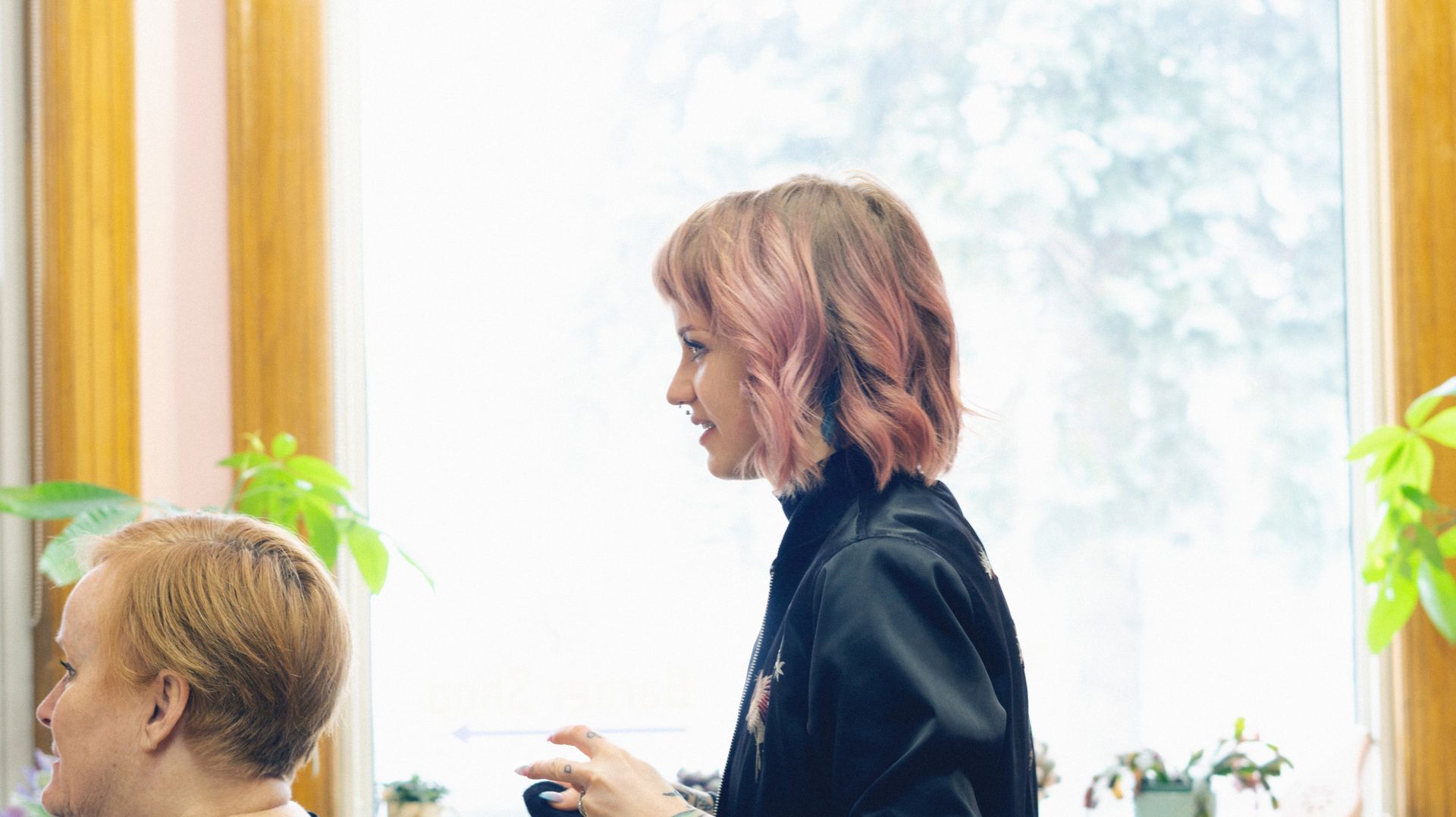 Owner and Stylist Emma Quinn working on a client’s hair in front of a big picture window.